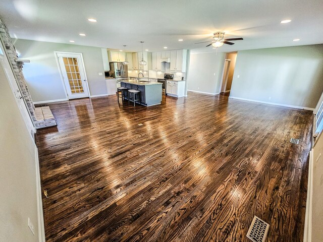 unfurnished living room featuring dark wood-style floors, recessed lighting, ceiling fan, and a sink