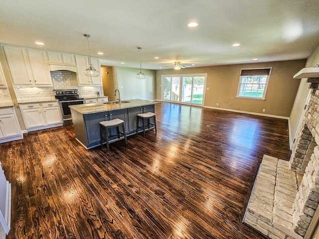 kitchen with dark wood-style floors, stainless steel electric stove, a sink, and a ceiling fan