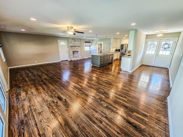 unfurnished living room with dark wood finished floors, a sink, plenty of natural light, and ceiling fan