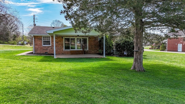 back of property with crawl space, brick siding, a shingled roof, a yard, and a patio area