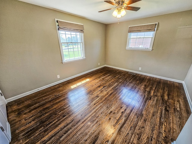 spare room featuring baseboards, wood finished floors, a ceiling fan, and plenty of natural light
