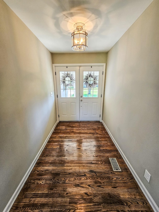 doorway featuring an inviting chandelier, dark wood-style floors, baseboards, and visible vents