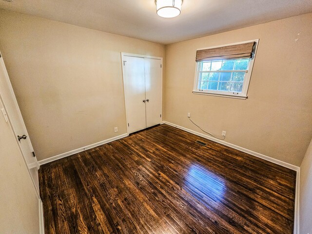 unfurnished bedroom featuring visible vents, baseboards, and wood finished floors