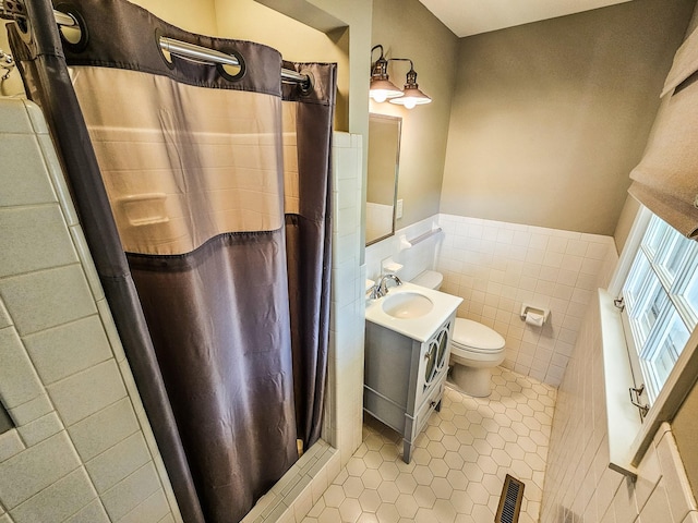 bathroom with tile walls, a wainscoted wall, visible vents, toilet, and vanity