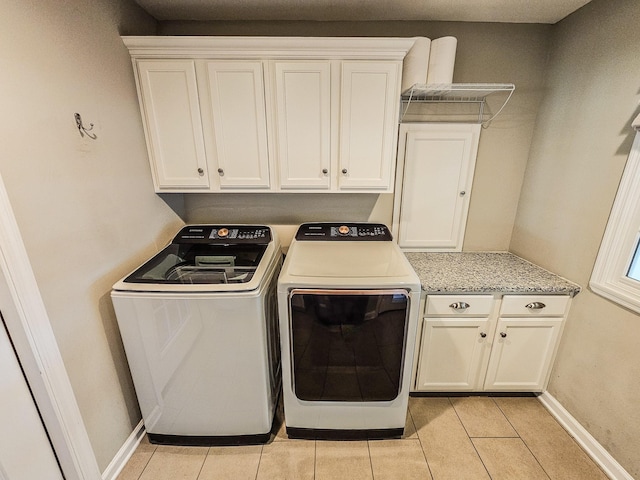 washroom with baseboards, washer and dryer, cabinet space, and light tile patterned floors