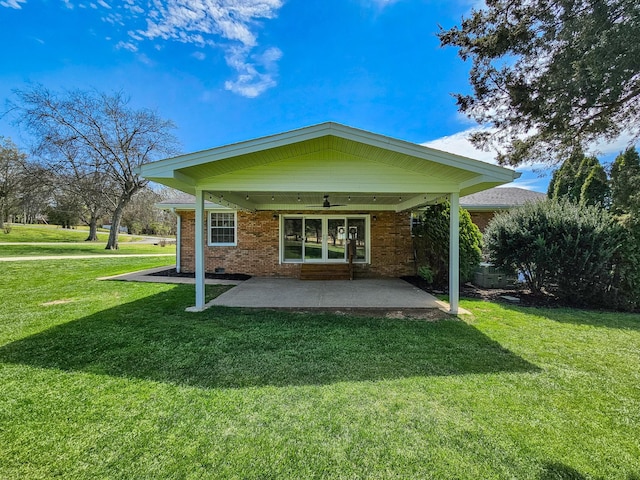 rear view of house with a lawn, ceiling fan, a patio area, and brick siding