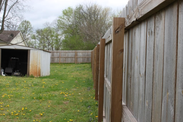 view of yard featuring an outbuilding, fence, and a shed