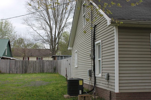 view of home's exterior with a lawn, central AC unit, and fence
