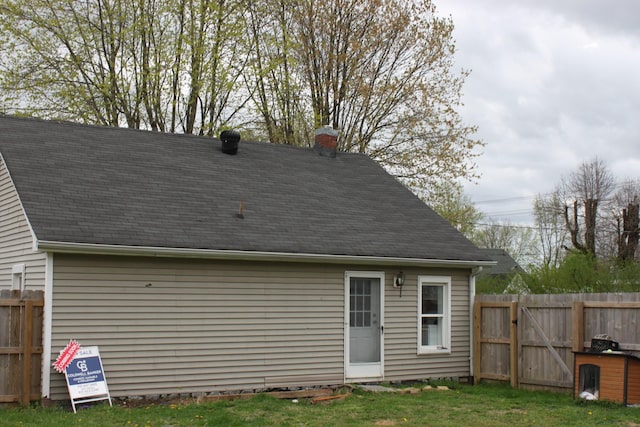 back of house with a yard, fence, and a chimney