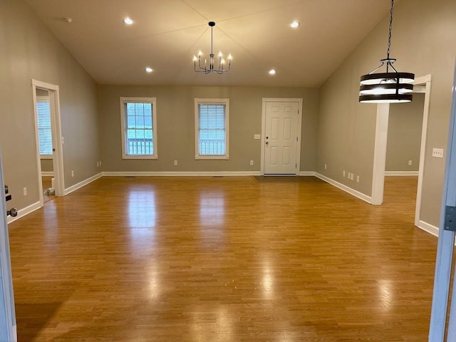 unfurnished living room featuring dark wood-style floors, vaulted ceiling, and an inviting chandelier