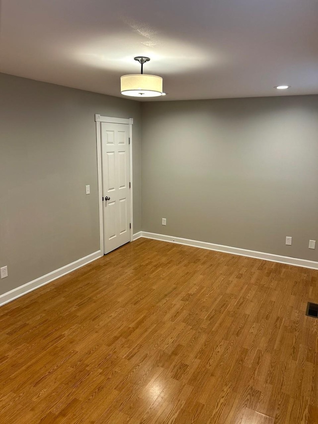 unfurnished room with baseboards, visible vents, and wood finished floors