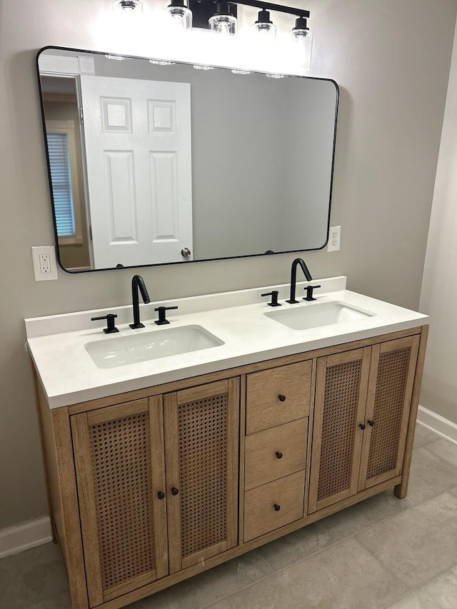 full bathroom featuring double vanity, a sink, and baseboards