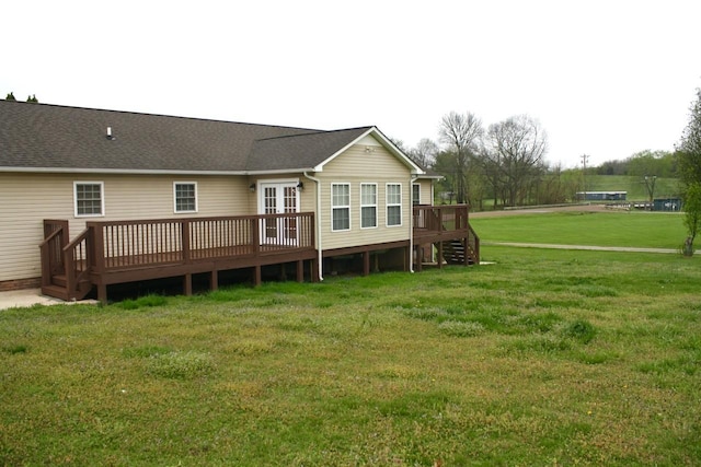 back of property featuring roof with shingles, a yard, and a wooden deck