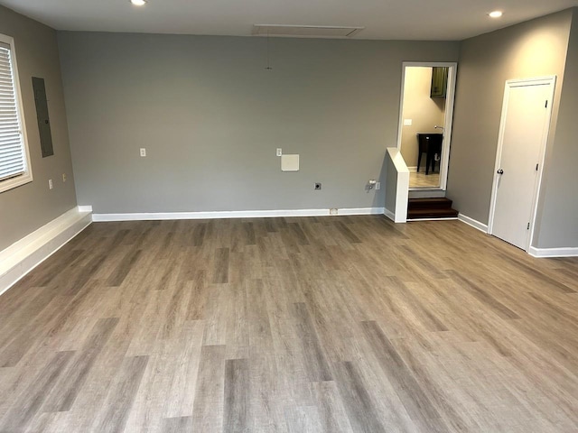 unfurnished living room with baseboards, wood finished floors, and attic access