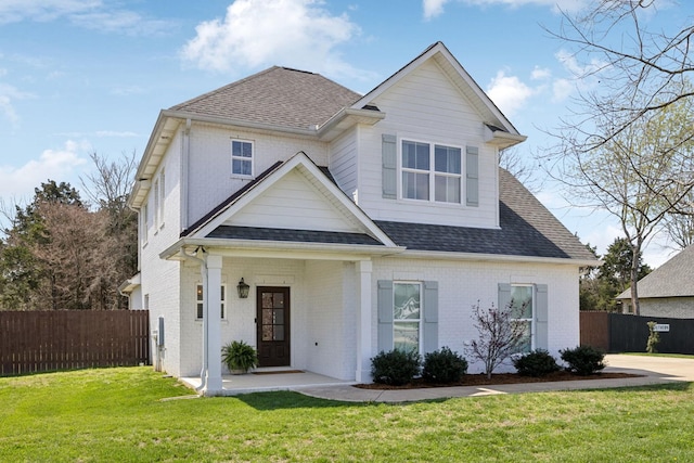 view of front of property with brick siding, a shingled roof, fence, and a front lawn