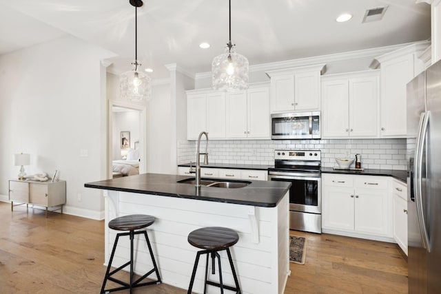 kitchen featuring dark countertops, a sink, stainless steel appliances, and visible vents
