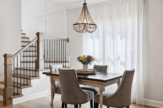 dining space featuring stairs, wood finished floors, a decorative wall, baseboards, and an inviting chandelier