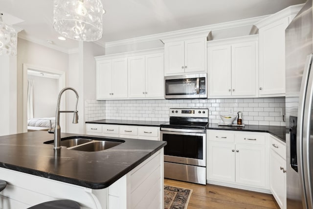 kitchen featuring white cabinets, dark countertops, appliances with stainless steel finishes, and crown molding