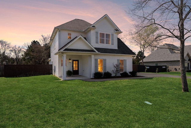 view of front of home with brick siding, fence, and a front lawn