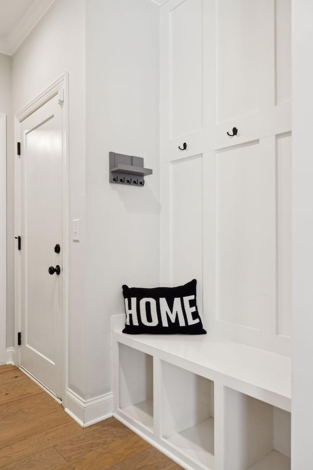 mudroom featuring crown molding, baseboards, and wood finished floors