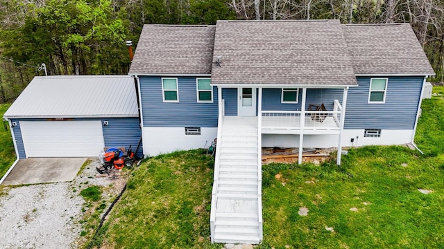 view of front of house with a garage, stairs, an outbuilding, a front lawn, and driveway