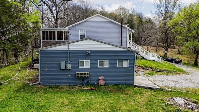 view of side of property featuring stairway and a lawn