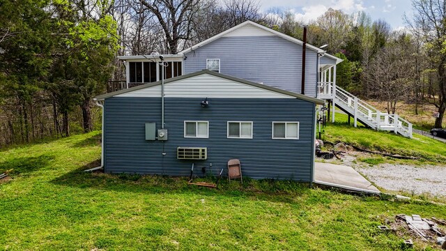 rear view of property with stairs and a lawn