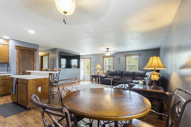 dining area with baseboards, light wood finished floors, and a textured ceiling
