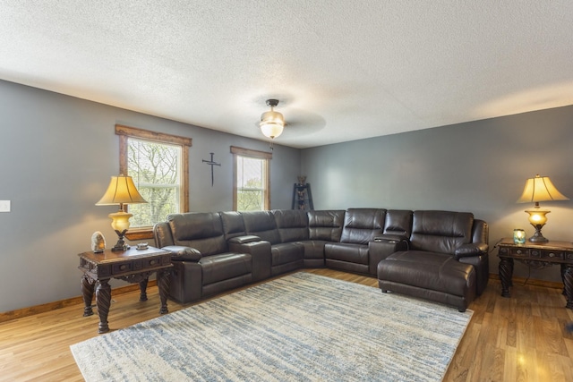 living area with a textured ceiling, wood finished floors, ceiling fan, and baseboards