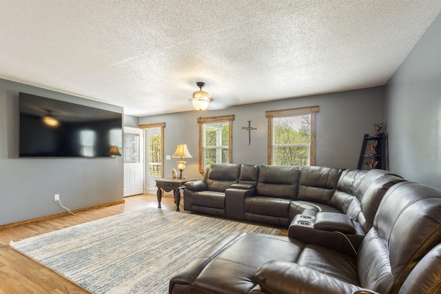 living room with ceiling fan, baseboards, wood finished floors, and a textured ceiling