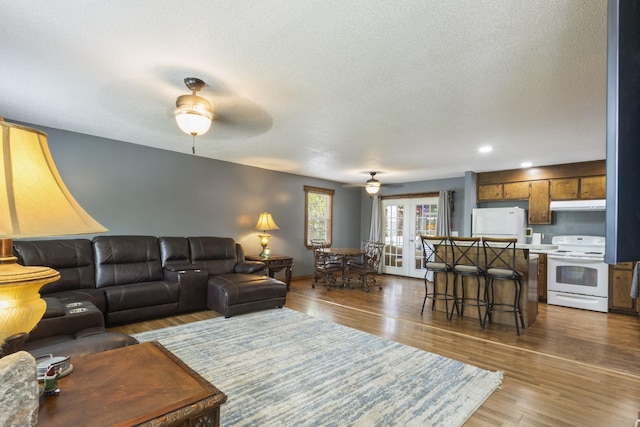 living area featuring a ceiling fan, a textured ceiling, recessed lighting, wood finished floors, and french doors