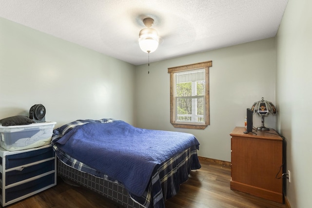 bedroom with baseboards, wood finished floors, and a textured ceiling
