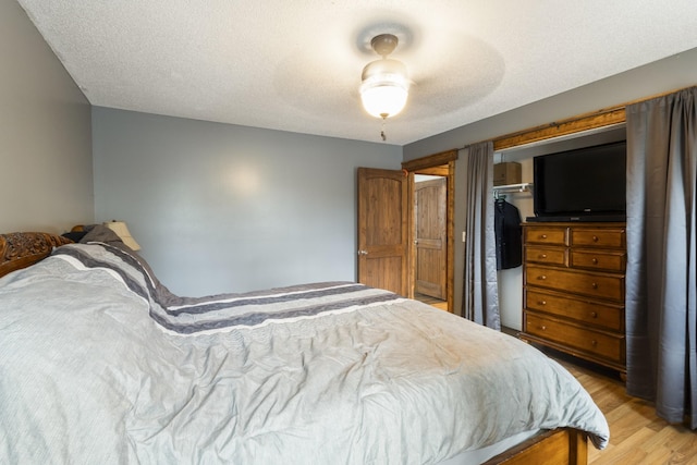 bedroom featuring ceiling fan, light wood finished floors, and a textured ceiling