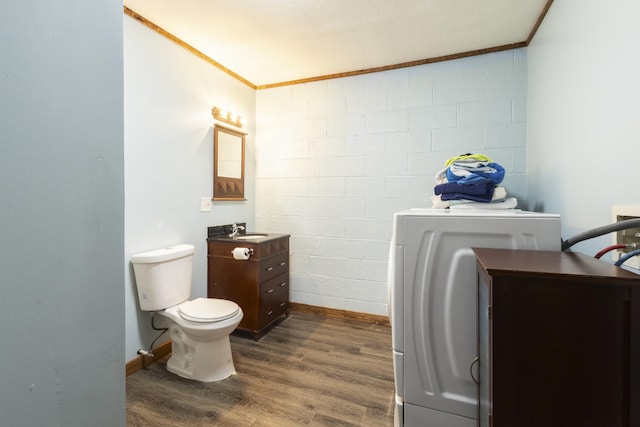 half bathroom featuring washer / clothes dryer, vanity, ornamental molding, toilet, and wood finished floors