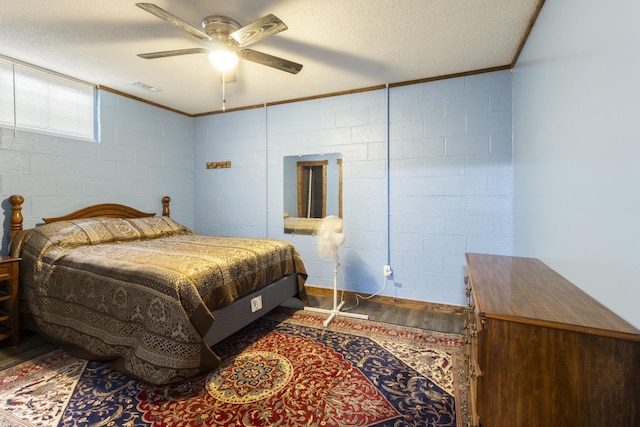 bedroom with visible vents, concrete block wall, wood finished floors, and a textured ceiling