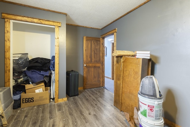 hall with a textured ceiling, ornamental molding, and wood finished floors