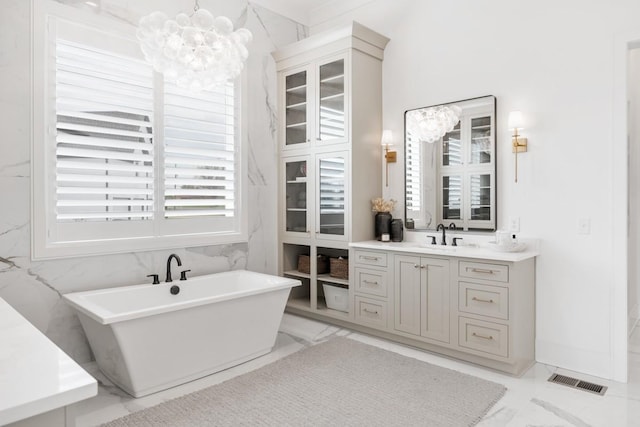 full bathroom featuring vanity, a soaking tub, marble finish floor, visible vents, and an inviting chandelier