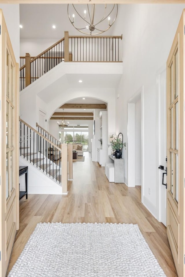 entryway featuring stairs, wood finished floors, arched walkways, and an inviting chandelier