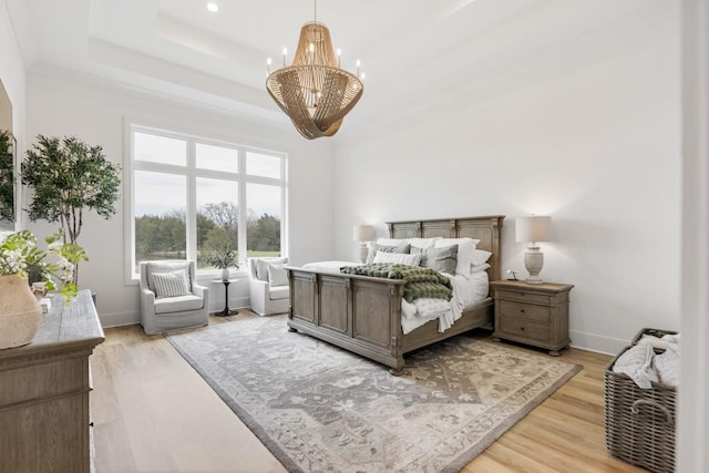 bedroom with an inviting chandelier, a raised ceiling, baseboards, and light wood-type flooring