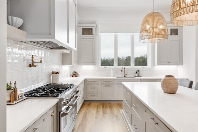 kitchen featuring decorative backsplash, custom exhaust hood, light wood-type flooring, range with two ovens, and an inviting chandelier