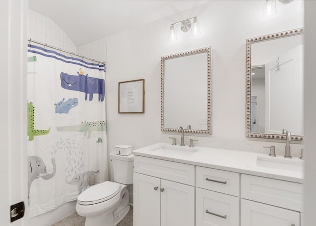 full bath with double vanity, vaulted ceiling, a sink, and toilet