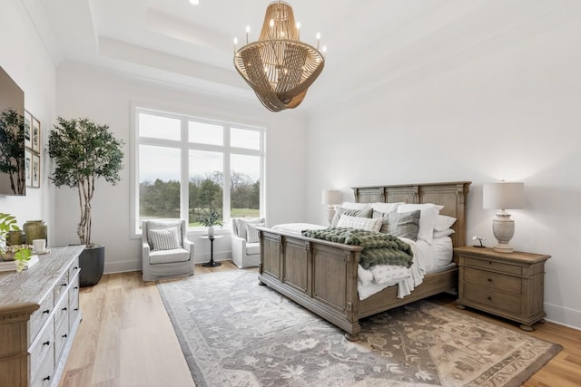 bedroom with baseboards, a tray ceiling, a chandelier, and light wood-style floors