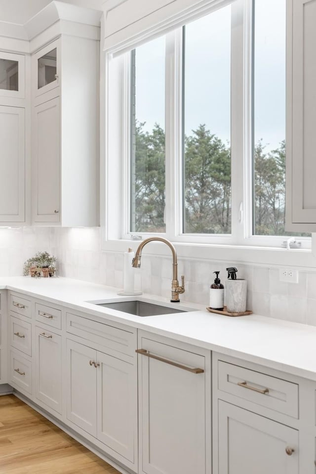 kitchen with plenty of natural light, tasteful backsplash, a sink, and white cabinets