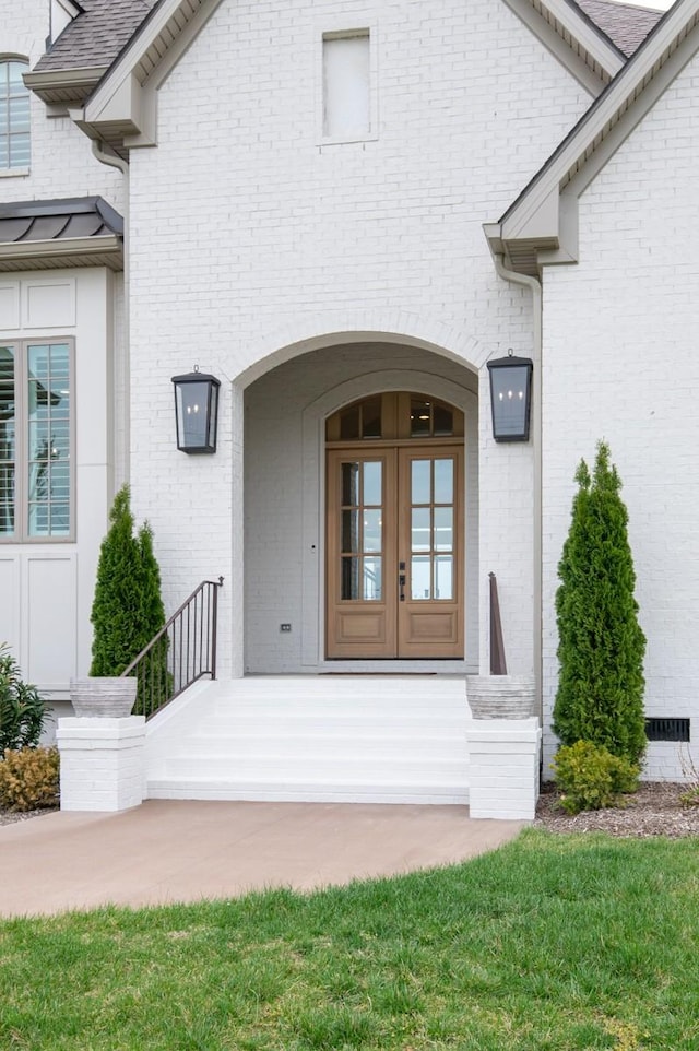 view of exterior entry featuring brick siding and french doors