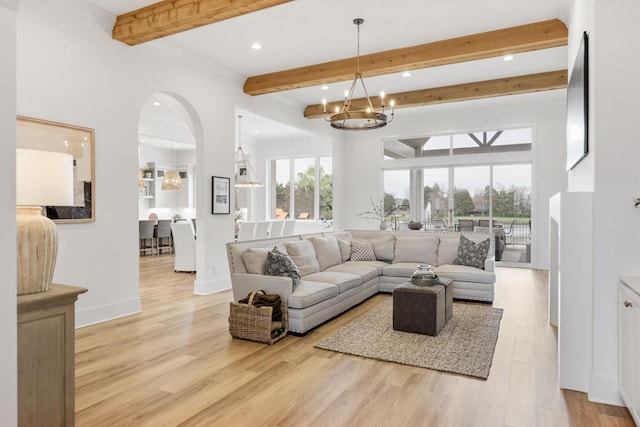 living room featuring baseboards, an inviting chandelier, light wood-type flooring, and beam ceiling