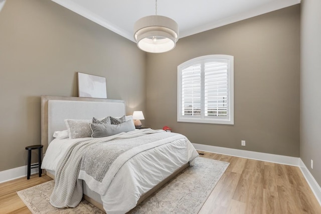 bedroom featuring light wood-style flooring, ornamental molding, and baseboards