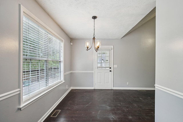 unfurnished dining area with hardwood / wood-style floors, baseboards, visible vents, and a chandelier