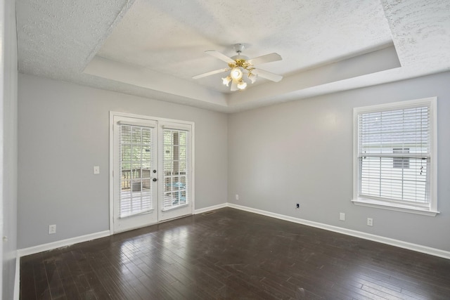 unfurnished room with french doors, a raised ceiling, and dark wood-type flooring