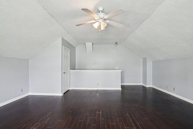 additional living space with vaulted ceiling, baseboards, a textured ceiling, ceiling fan, and wood finished floors