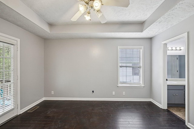 empty room featuring dark wood finished floors, baseboards, plenty of natural light, and a ceiling fan